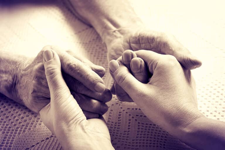 Caregiver holding hands of Senior man